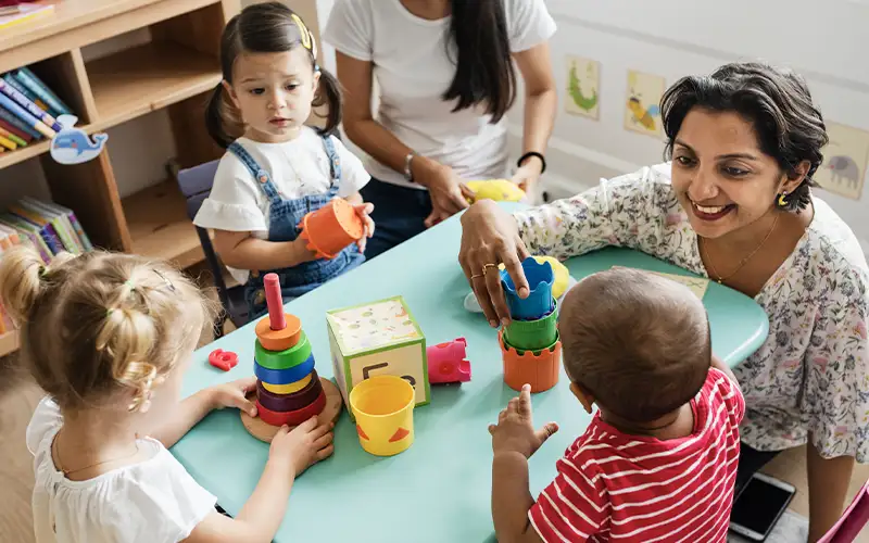 nursery teacher and children playing with wooden toys